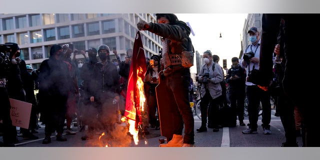 A counter-protester burns a Trump 2020 flag after supporters of President Donald Trump held pro-Trump marches on Saturday in Washington. (AP Photo/Jacquelyn Martin)