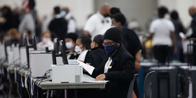 Volunteers wearing protective masks process absentee ballots for the 2020 presidential election at the TCF Center in Detroit Nov. 4, 2020.