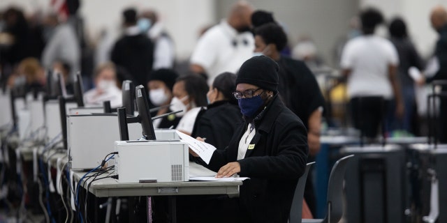 Volunteers wearing protective masks process absentee ballots for the 2020 presidential election at the TCF Center in Detroit Nov. 4, 2020.