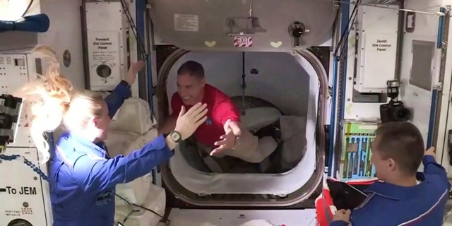 In this frame grab from NASA TV, astronaut Mike Hopkins, center, is greeted by astronaut Kate Rubins, left, as he enters the International Space Station from the vestibule between the SpaceX Dragon capsule and the ISS, early Tuesday, Nov. 17, 2020. At right is Expedition 64 commander Sergey Ryzhikov.