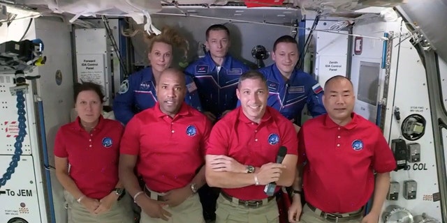 У цьому кадрі захоплення телевізора NASA, екіпажу SpaceX Dragon, спереду ліворуч праворуч, стоять Шеннон Уокер, Віктор Гловер, Майк Хопкінс і Соїчі Ногучі з екіпажем Міжнародної космічної станції Кейт Рубінс, зліва ззаду, командир експедиції 64 Сергій Рижиков та Сергій Куд -Сверчков під час вітальної церемонії, на початку вівторка, 17 листопада 2020 року. Дракон прибув і причалив до МКС пізно в понеділок.  (NASA TV через AP)