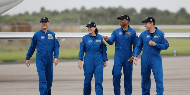 Astronaut Soichi Noguchi of Japan, left to right, NASA astronauts Shannon Walker, Victor Glover and Michael Hopkins walk after arriving at the Kennedy Space Center on Sunday, November 8, 2020, in Cape Canaveral, Florida.