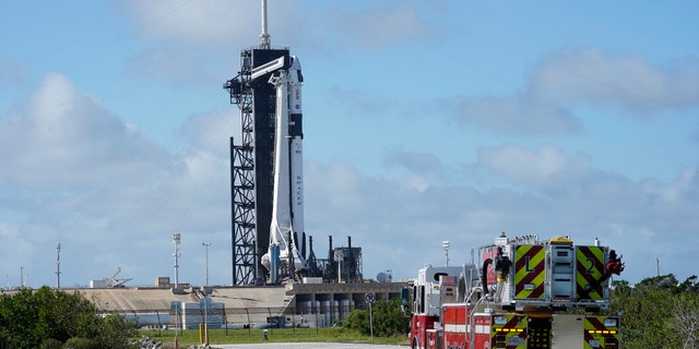 NASA firefighters drive on the road outside the fence near a SpaceX Falcon 9 rocket, with the company's Crew Dragon capsule attached, sits on the launch pad at Launch Complex 39A Friday, Nov. 13, 2020, at the Kennedy Space Center in Cape Canaveral, Fla.
