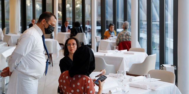 A waiter tends to patrons in the Mediterranean seafood restaurant Estiatorio Milos at the Hudson Yards in Manhattan, New York, Sept. 30, 2020. (REUTERS/Andrew Kelly)