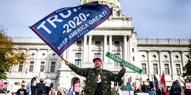 A man waves a flag at a pro-Trump rally at the Pennsylvania state Capitol in Harrisburg, Pa., Nov. 5. (Dan Gleiter/The Patriot-News via AP)