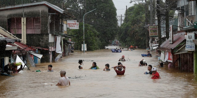 Due to Typhoon Vamco on Thursday, November 12, 2020, the Marikina, Philippines, floods continue to rise, and residents are negotiating a flooded road.