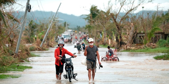 On Thursday, November 12, 2020, due to Typhoon Vamco, residents walked past overturned electric poles along a flooded road in Albay Province in the central Philippines.