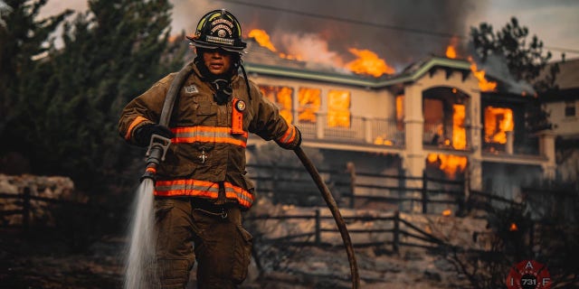A firefighter helps to battle a blaze that engulfed a home in a Reno neighborhood on Tuesday.