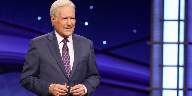 Alex Trebek in a dark suit and purple tie on "Jeopardy"