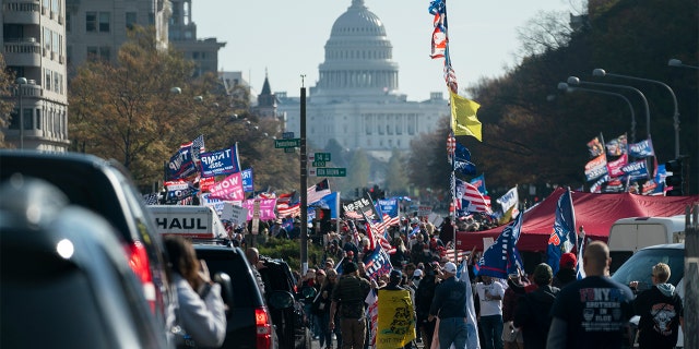 A motorcade carrying President Donald Trump drives by a group of supporters participating in a rally near the White House, Saturday, Nov. 14, 2020, in Washington. (AP Photo/Evan Vucci)