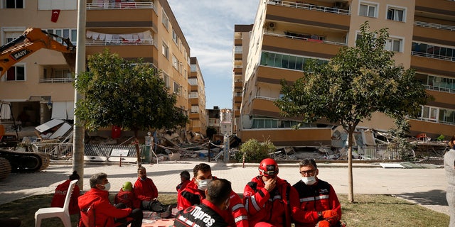 Members of rescue services take a break during search operations in the debris of a collapsed building for survivors in Izmir, Turkey, Sunday, Nov. 1, 2020.
