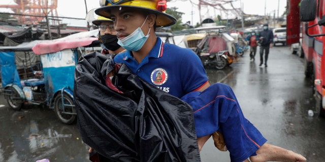 A rescuer carries a sick child as they evacuate residents living along a coastal community in Manila, Philippines on Sunday, Nov. 1, 2020. (Associated Press)