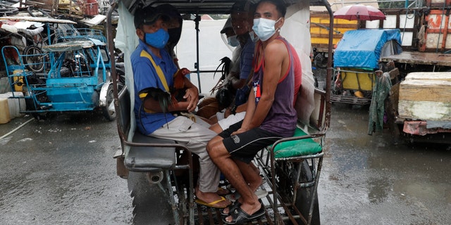 Residents wearing face masks to help prevent the spread of the coronavirus evacuate with their chickens to safer grounds as rains from a typhoon locally known as Goni start to pour in Manila, Philippines on Sunday Nov. 1, 2020. (Associated Press)