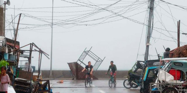 Residents walk past a toppled structure as waves batter the coast of Sorsogon province, central Philippines as Typhoon Goni hits the country on Sunday, Nov. 1, 2020. (Associated Press)
