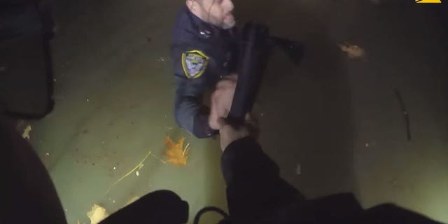 An officer holds onto another officer in the chilly river water while working to help the trapped woman. 