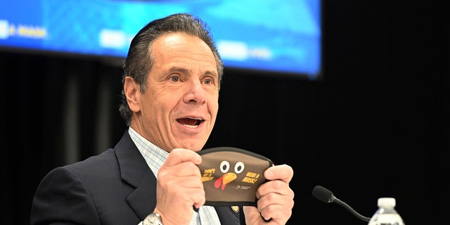 In it provided by New York State, New York Governor Andrew Cuomo holds up a new Thanksgiving-themed face mask during his daily coronavirus briefing at Wyandanch-Wheatley Heights Ambulance Corp. headquarters in Wyandanch, New York (Kevin P. Coughlin / New York State via AP)