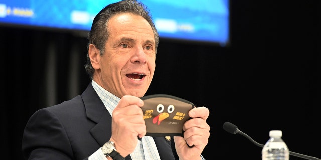 In this New York State supply, New York Governor Andrew Cuomo is putting on a new Thanksgiving-themed face mask during his daily coronavirus briefing at the Wyandanch-Wheatley Heights Ambulance Corp. headquarters.  in Wyandanch, NY (Kevin P. Coughlin / New York State via AP)