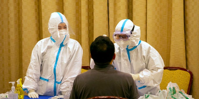 Workers in protective suits administer a COVID-19 test in Wenchang in southern China's Hainan Province on Sunday. (AP Photo/Mark Schiefelbein)