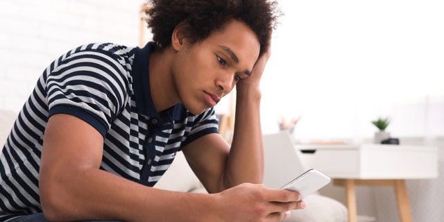 A young man looks at his smartphone screen at home. Especially during the holidays, people who are struggling with mental health issues can feel a sense of isolation, said one expert.