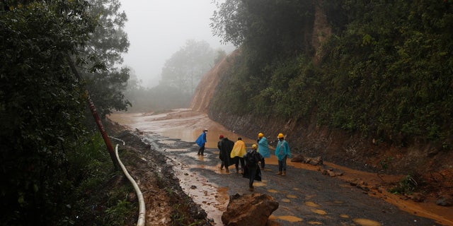 Workers walk around a road blocked by a landslide in San Cristobal Verapaz, Saturday, Nov. 7, 2020, in the aftermath of Hurricane Eta.