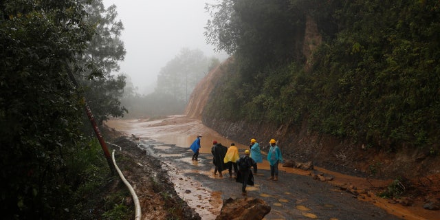 Workers walk around a road blocked by a landslide in San Cristobal Verapaz, Saturday, November 7, 2020, after hurricane Eta.