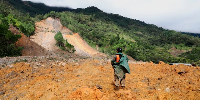 A member of a search and rescue team looks for survivors through the destruction caused by a massive, rain-fueled landslide in the village of Queja, in Guatemala, Saturday, Nov. 7, 2020, in the aftermath of Tropical Storm Eta. 