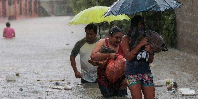 Residents wade through a flooded road carrying some belongings in Progreso Yoro, Honduras, Wednesday, Nov. 4, 2020.