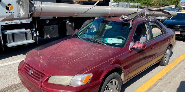 In this photo provided by the Florida Highway Patrol a downed power pole is strapped to the roof of a car, Monday, Nov. 16, 2020, on Interstate 4, in Hillsborough County, Fla. (Florida Highway Patrol via AP)