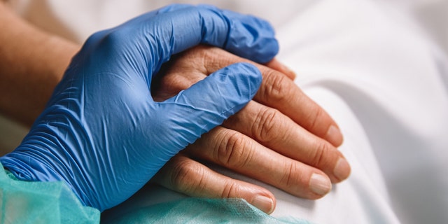 A doctor's hand on a patient's hand (iStock)