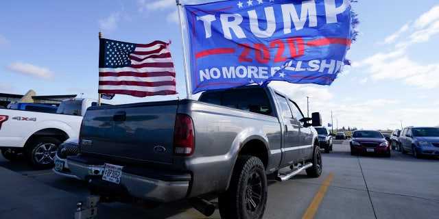Flags fly over a pickup truck outside a President Donald Trump campaign rally at Dubuque Regional Airport, Sunday, Nov. 1, 2020, in Dubuque, Iowa.