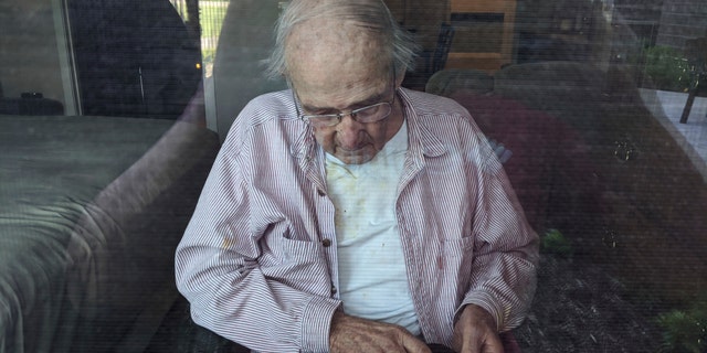 This June 7, 2020, photo provided by June Linnertz shows her father, James Gill, seen through a window at Cherrywood Pointe nursing home in Plymouth, Minn.