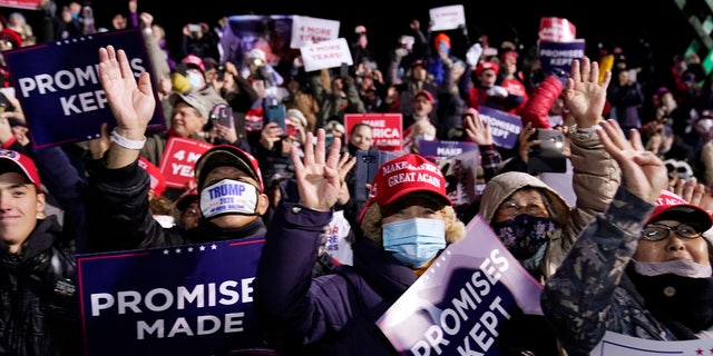 Trump supporters hold up four fingers as they chant 'Four More Years' at President Trump's campaign rally in Butler, Pa. Saturday.