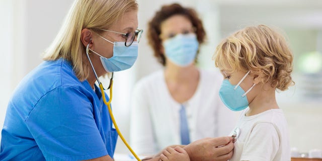 A child receives a checkup from a physician. 