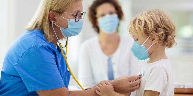 A child receives a checkup from a physician. 