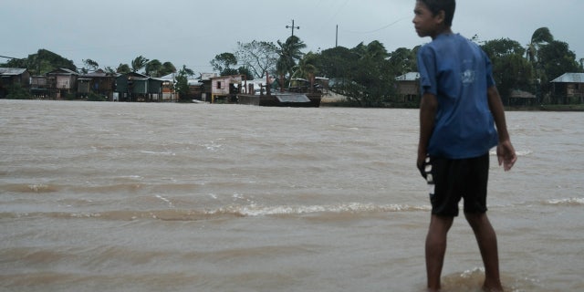 A boy looks over at the river inundated with floodwaters brought on by Hurricane Eta in Wawa, Nicaragua, Tuesday, Nov. 3, 2020.