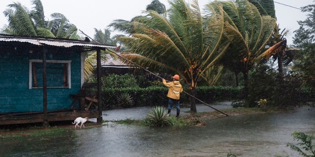 A man fixes the roof of a home surrounded by floodwaters brought on by Hurricane Eta in Wawa, Nicaragua, Tuesday, Nov. 3, 2020.