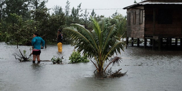 Residents stand outside a home surrounded by floodwaters brought on by Hurricane Eta in Wawa, Nicaragua, Tuesday, Nov. 3, 2020.