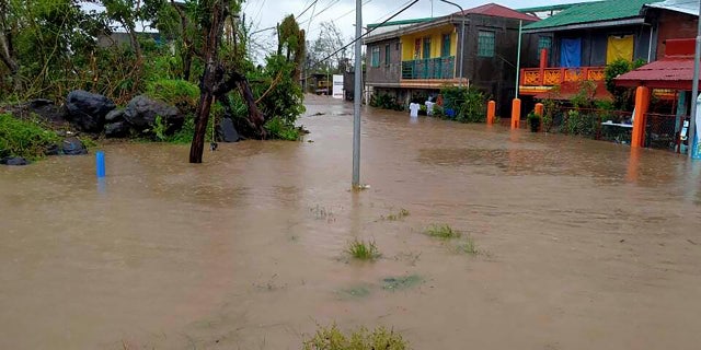 Residents walk along floodwaters in Daraga, Albay province, central Philippines as Typhoon Goni hit the area on Sunday Nov. 1, 2020.