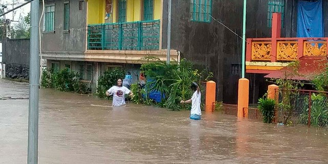 Residents walk along floodwaters in Daraga, Albay province, central Philippines as Typhoon Goni hit the area Sunday, Nov. 1, 2020.