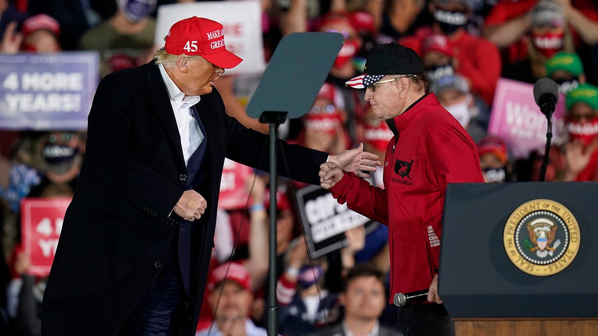 FILE - In this Oct. 14, 2020 file photo, President Donald Trump greets former University of Iowa wrestling coach Dan Gable, right, during a campaign rally at Des Moines International Airport in Des Moines, Iowa. (AP Photo/Charlie Neibergall)