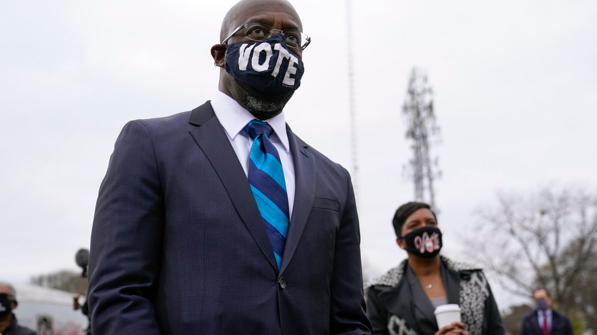 Georgia Democratic candidate for U.S. Senate Raphael Warnock listens as President-elect Joe Biden speaks at a drive-in rally for Warnock and Jon Ossoff, Tuesday, Dec. 15, 2020, in Atlanta. (AP Photo/Patrick Semansky)