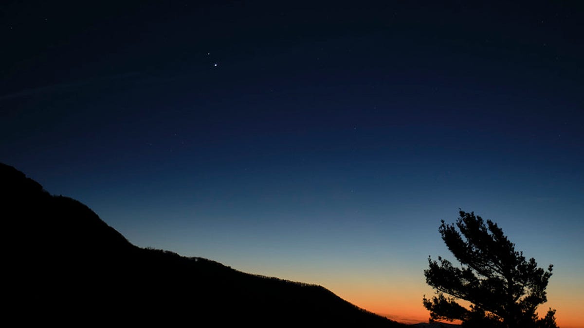 Saturn, top, and Jupiter, below, are seen after sunset from Shenandoah National Park, Sunday, Dec. 13, 2020, in Luray, Virginia. The two planets are drawing closer to each other in the sky as they head towards a "great conjunction" on December 21, where the two giant planets will appear a tenth of a degree apart. Photo Credit: (NASA/Bill Ingalls)