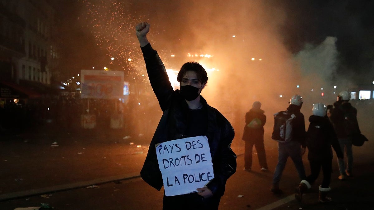 A protester holds a poster reading "Land of rights for the police" during a demonstration against a security law Saturday, Nov. 28, 2020 in Paris. Thousands of critics of a proposed security law that would restrict sharing images of police officers in France gathered across the country in protest, and officers in Paris who were advised to behave responsibly during the demonstrations fired tear gas to disperse rowdy protesters in the largely peaceful crowd. The cause has gained fresh impetus in recent days after footage emerged of French police officers beating up a Black man, triggering a nationwide outcry. (AP Photo/Francois Mori)