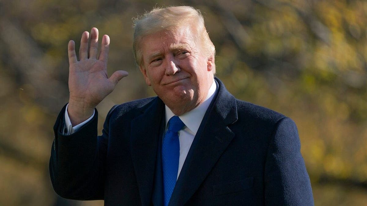 Former president Donald Trump waves to camera while wearing a suit