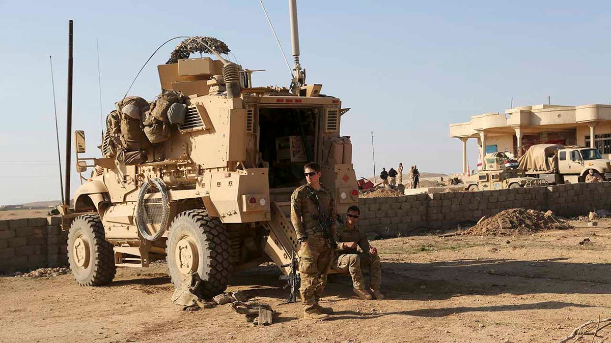 In this Feb. 23, 2017 file photo, U.S. Army soldiers stand outside their armored vehicle on a joint base with the Iraqi army, south of Mosul, Iraq. In a quest to root out Islamic State group hideouts over the summer, Iraqi forces on the ground cleared nearly 90 villages across a notoriously unruly northern province. But the much-touted operation still relied heavily on U.S. intelligence, coalition flights and planning assistance. (AP Photo/ Khalid Mohammed, File)