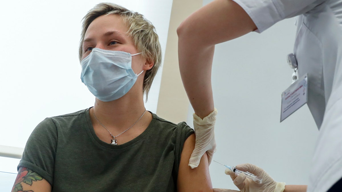 Russian medical worker, right, administers a shot of Russia's Sputnik V coronavirus vaccine in Moscow, Russia, Saturday, Dec. 5, 2020. Thousands of doctors, teachers and others in high-risk groups have signed up for COVID-19 vaccinations in Moscow starting Saturday, a precursor to a sweeping Russia-wide immunization effort. (AP Photo/Pavel Golovkin)