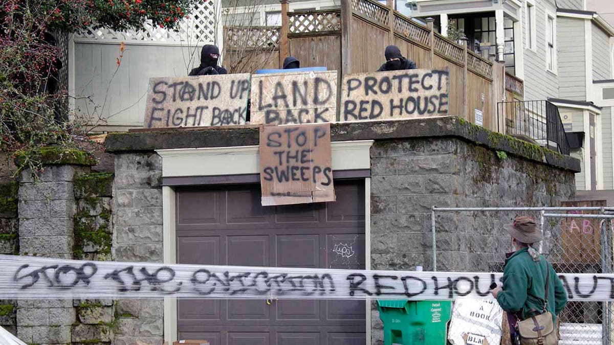 Masked protesters by an occupied home speak with a neighborhood resident opposed to their encampment and demonstration in Portland, Ore., on Wednesday, Dec. 9, 2020.  (AP Photo/Gillian Flaccus)