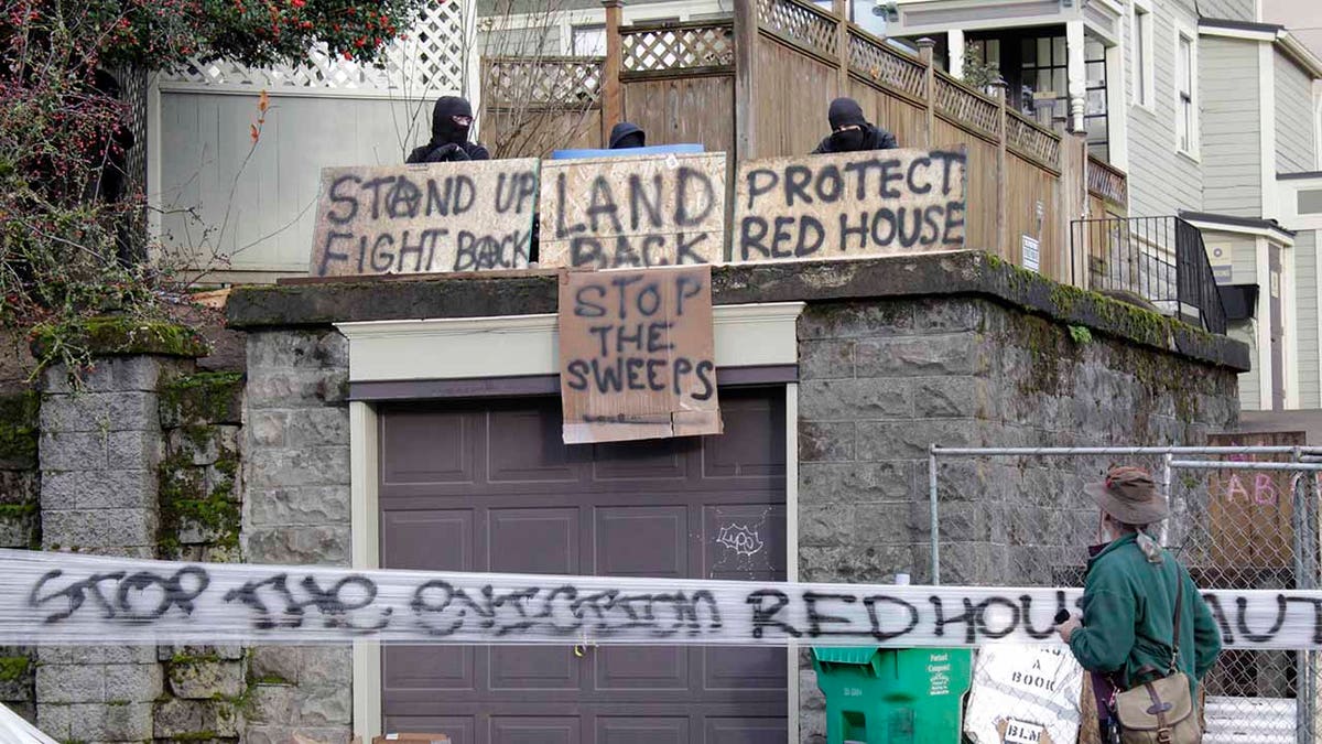 Masked protesters by an occupied home speak with a neighborhood resident opposed to their encampment and demonstration in Portland, Ore., on Wednesday, Dec. 9, 2020.? (AP Photo/Gillian Flaccus)