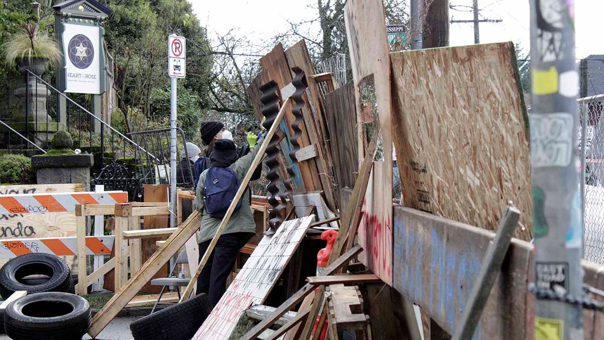 Protesters reinforce their barricades at an encampment outside a home in Portland, Ore., on Wednesday, Dec. 9, 2020. (AP Photo/Gillian Flaccus)