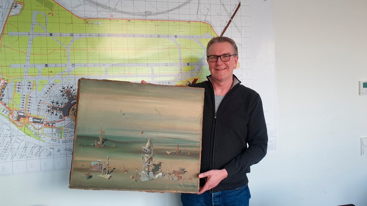 Chief Detective Michael Dietz poses with the recovered painting by French artist Yves Tanguy. (Polizei Duesseldorf via AP)
